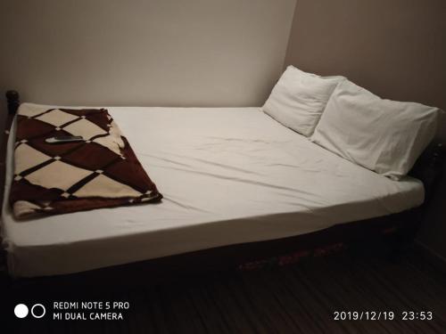 钦奈Sai Baba Service Apartments的一张带白色床单和棕色的未铺好的床
