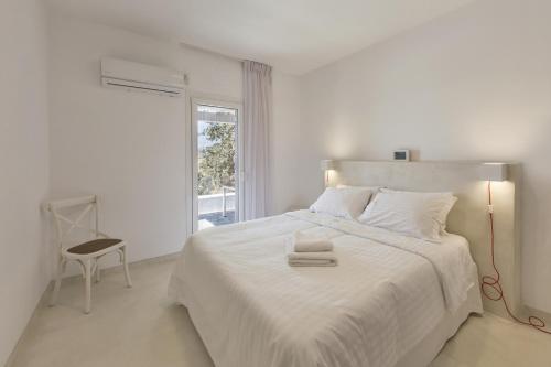 KoundourosApartment with a sea view and swimming pool, in the area of Koundouros的白色卧室配有一张白色的大床和一把椅子