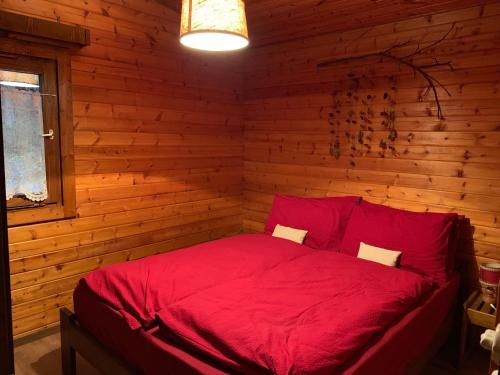 萨洛尔诺Chalet San Valentino的小木屋内一间卧室,配有红色的床