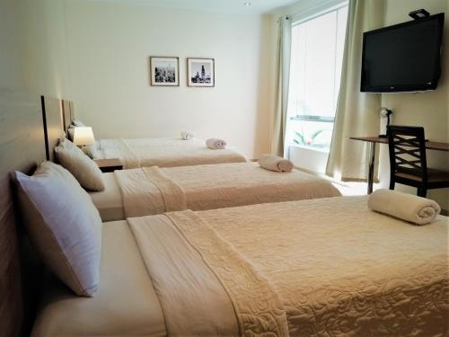 伊察Villa Oasis的配有平面电视的客房内的两张床