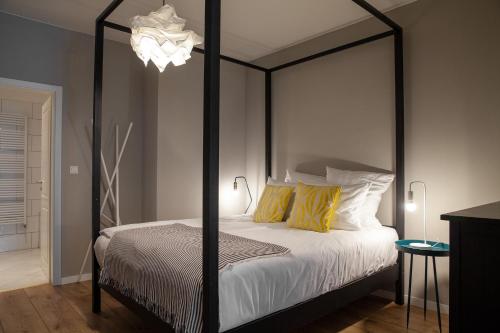 美因河畔法兰克福法布里克套房酒店 的一间卧室配有黑色天蓬床和黄色枕头