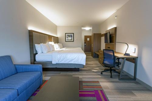 哥伦布Holiday Inn Express & Suites - Columbus - Worthington, an IHG Hotel的酒店客房配有一张床、一张书桌和一张沙发。