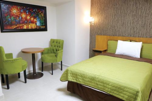 马德罗城Royal Madero Inn的一间卧室配有绿色的床和桌椅