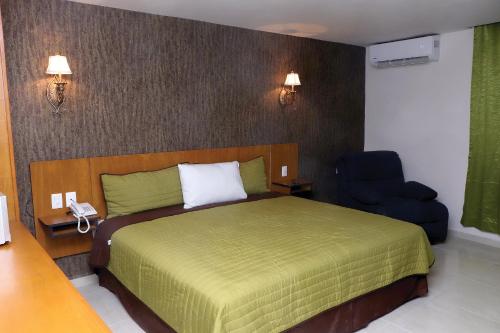 马德罗城Royal Madero Inn的一间卧室配有绿色的床和蓝色椅子