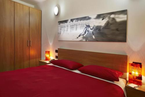 塞斯特雷Teleo Vacanze - Villaggio Olimpico di Sestriere的一间卧室配有红色的床和两个红色枕头