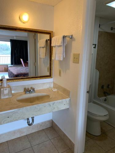艾伦港Baton Rouge West Inn的一间带水槽、镜子和卫生间的浴室