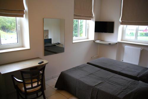 Senningerberg查理火车站旅馆的一间卧室配有一张床、一张书桌和一面镜子