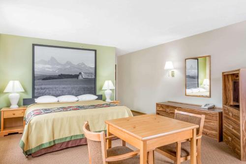 德里格斯Super 8 by Wyndham Driggs的酒店客房配有一张床铺、一张桌子和一张书桌。