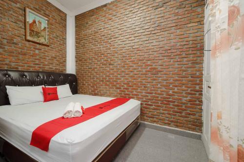 先达RedDoorz Syariah near Jalan Asahan Pematang Siantar的一间卧室设有砖墙和一张带拖鞋的床