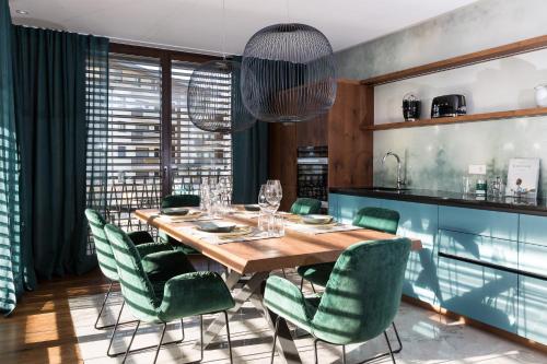 布鲁尼科ANTON Dolomites Hideaway的一间带木桌和绿色椅子的用餐室