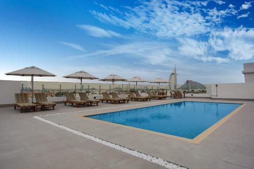 迪拜Lemon Tree Hotel, Jumeirah Dubai的屋顶上带椅子和遮阳伞的游泳池