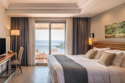 塞沃塔多莫特贴水尼古拉斯套房度假酒店的一间带一张床和一张书桌的卧室以及一个阳台