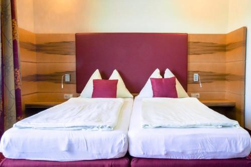 佩尔森贝格迪多瑙拉斯特费施沃特豪斯兰德汽车旅馆的两张位于酒店客房的床,配有红色和白色枕头