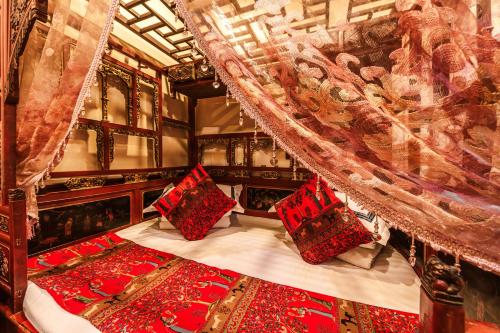 平遥Pingyao Hongyuyuan Guesthouse的一间卧室配有一张带红色枕头的天蓬床
