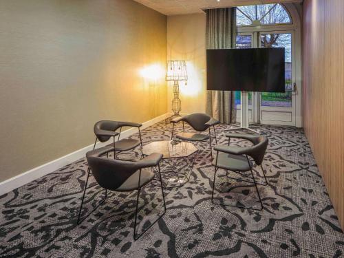 昂古莱姆法国昂古莱姆美居酒店的一间设有四把椅子和一台平面电视的房间