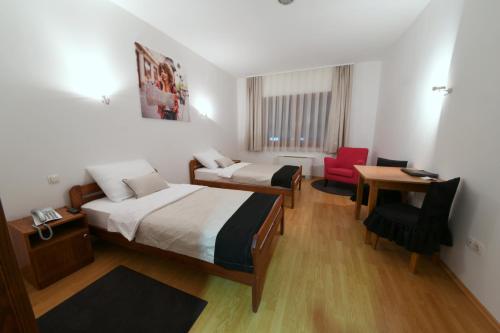 Križevci克里热夫齐公寓酒店的客房设有两张床、一张桌子和一把椅子。
