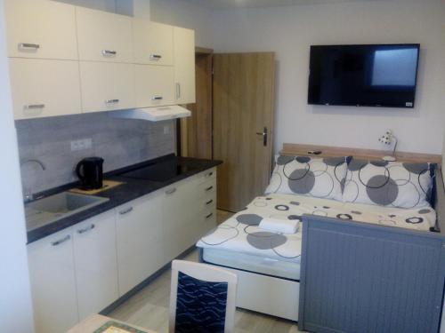 VacenoviceOaza的一间带白色橱柜的厨房和一张带水槽的床