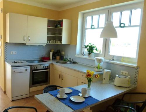 伯尔格伦德-雷特维施“斯特兰德-加特公寓”的厨房配有白色橱柜和鲜花桌
