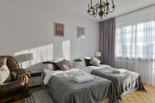 华沙Medicover Wilanow P&O Serviced Apartments的一间卧室配有两张床、一把椅子和一个吊灯。