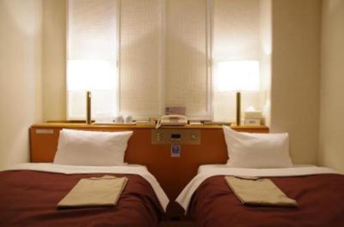 高山Country Hotel Takayama - Vacation STAY 67710的配有两张床铺、两盏灯和一部电话的客房