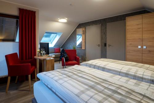 Irrhausen茵佩芬餐厅宾馆的酒店客房,配有一张床和两张红色椅子