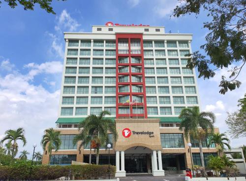 怡保Travelodge Ipoh的一座大型酒店,拥有一座棕榈树的红色建筑