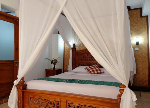 姆杜克KARANG SARI Guesthouse的卧室配有带白色窗帘的天蓬床