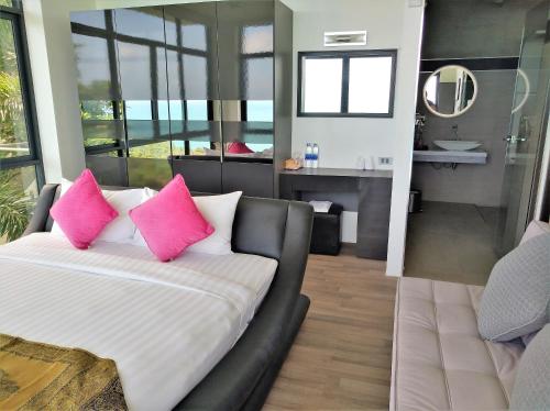 茶云莱海滩Villa Seawadee - luxurious, award-winning design Villa with amazing panoramic seaview的一间带粉色枕头沙发的卧室和一间浴室