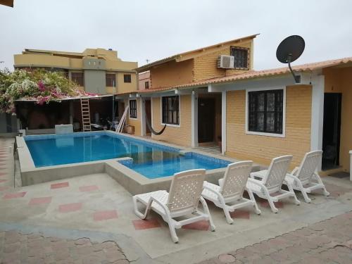 普拉亚斯Casa Hospedaje Playas的一个带椅子的游泳池以及一座房子