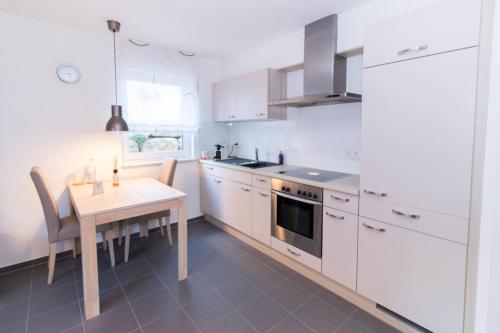 诺伊恩斯塔特阿姆科黑尔Appartement Neuenstadt in ruhiger Lage im Wohngebiet的厨房配有白色橱柜、餐桌和用餐室