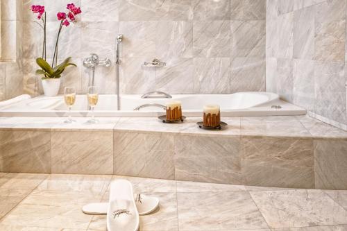 卡尔季察多莫特阿尼酒店的带浴缸和两杯香槟的浴室