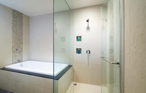 曼谷曼谷莎玛素坤逸服务式公寓的浴室配有带浴缸的玻璃淋浴间