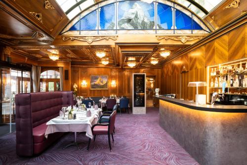 采尔马特采尔马特霍夫大酒店的餐厅设有桌椅和玻璃天花板