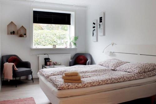 霍尔斯特布罗Nordkap Bed & Bath的一间卧室配有一张带两把椅子的床和一扇窗户