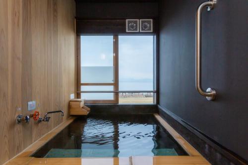 云仙市Iseya, Seaview Private Onsen Bath的浴室内设有带水池的浴缸室