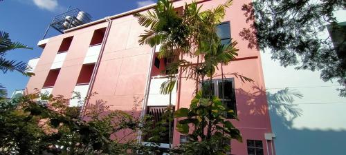 合艾TK Thongrak Apartment的前面有树木的粉红色建筑