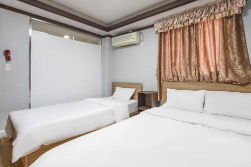 首尔柯姆康汽车旅馆的带窗户的客房内的两张床