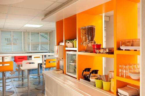 蒙德维尔东卡昂 - 蒙德维尔普瑞米尔经典酒店的厨房配有橙色和黄色橱柜和椅子