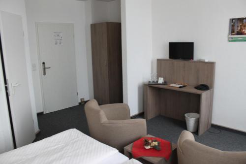开姆尼茨萨彻瑟斯查尔酒店的客房设有2把椅子和1张带电视的书桌。