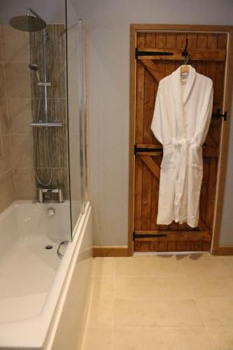 灵伍德Blashford Manor Farmhouse - The Shetland Cottage的一间带淋浴的浴室和门上的白色浴袍