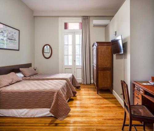 布宜诺斯艾利斯Bar de Fondo Suites的一间卧室配有两张床、一张桌子和一台电视。