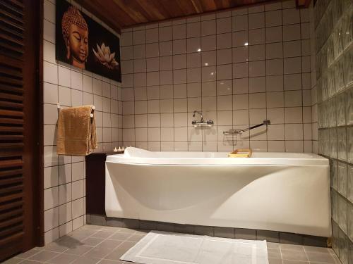 帕拉马里博Prins Hendrik Suites的浴室设有白色浴缸,浴室设有瓷砖墙