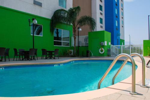 萨尔蒂约萨尔蒂约佐纳航空港智选假日酒店的一座带绿色墙壁的建筑前的游泳池