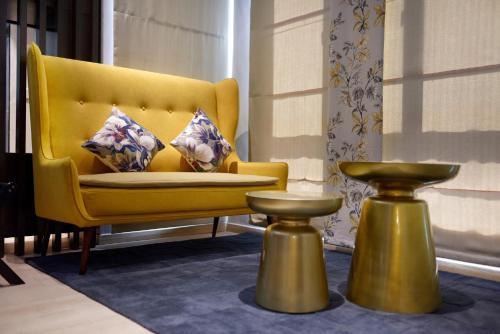 怡保Sojourn Spa Hotel Ipoh的黄色椅子,配有两个枕头和一张桌子