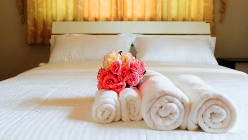 武里南Narakorn House的床上有毛巾和玫瑰花