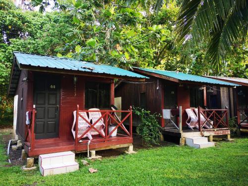 刁曼岛Puteri Salang Inn的一座红色的小房子,设有门廊和两把椅子