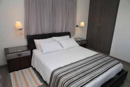 尼科西亚尼科西亚罗德斯公寓式酒店的一间卧室配有一张带2个床头柜的大型白色床