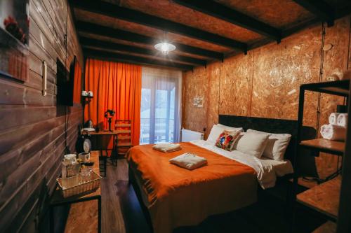 卡兹贝吉Wooden Hotel Kazbegi的一间卧室配有一张带橙色毯子的床