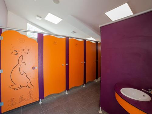 圣马迪拉莫Oh! Campings - Le Clos du Rhône的浴室的墙上有一条狗,上面有橙色和紫色的摊位
