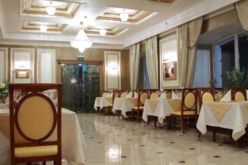 波尔塔瓦Hotel Aristokrat的一间在房间内配有桌椅的餐厅